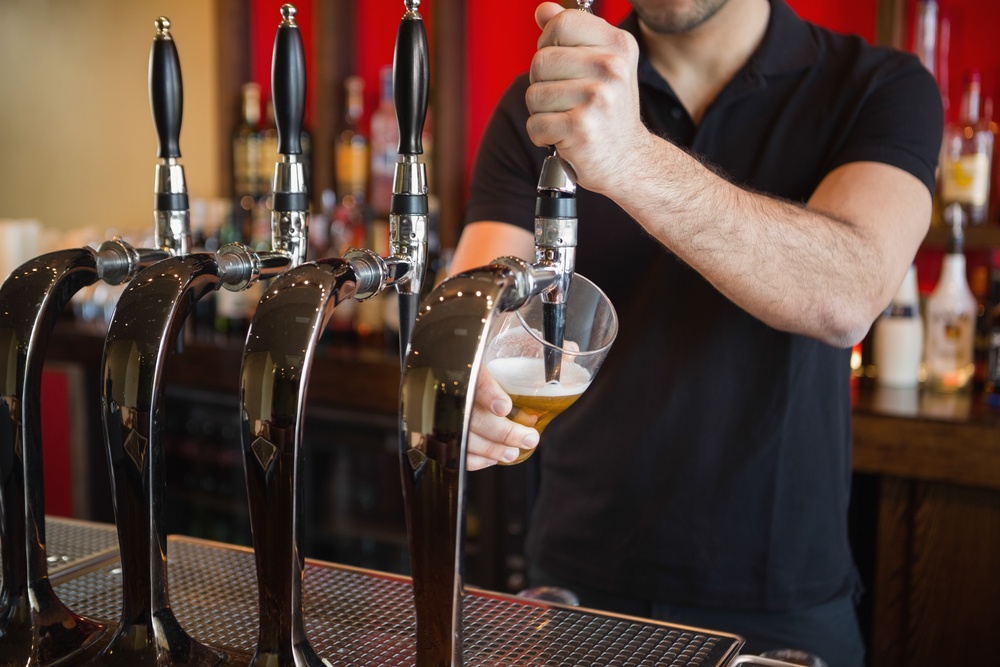 Barkeeper pulling a pint of beer behind the bar-1